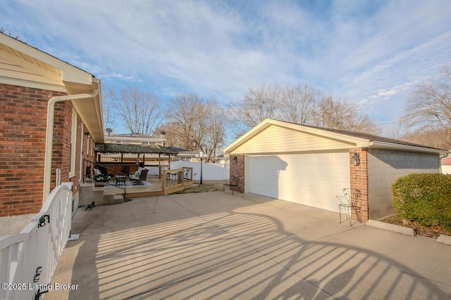 exterior space with a garage, brick siding, an outdoor structure, and a deck