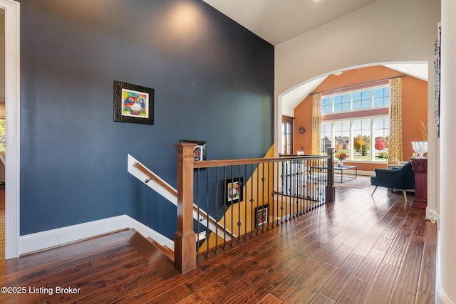 interior space with baseboards, arched walkways, and wood finished floors