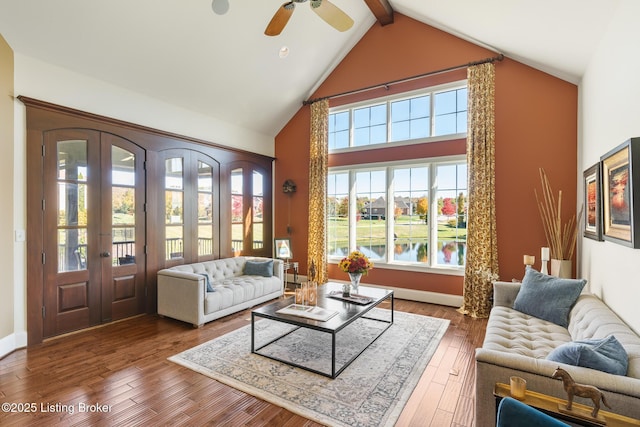 living area with dark wood-type flooring, a healthy amount of sunlight, a water view, and high vaulted ceiling