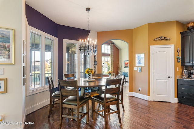 dining space with dark wood-style flooring, a healthy amount of sunlight, and a notable chandelier