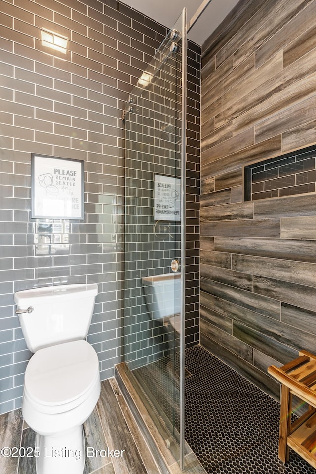 full bathroom featuring wood finished floors, a tile shower, and toilet