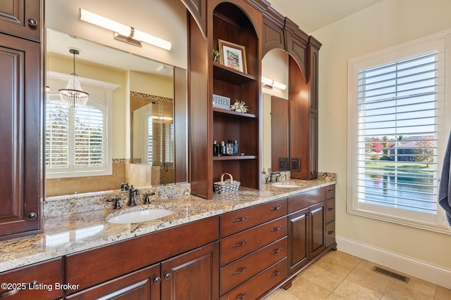 bathroom with double vanity, baseboards, visible vents, and a sink