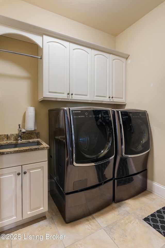 laundry area with cabinet space, baseboards, washer and clothes dryer, and a sink