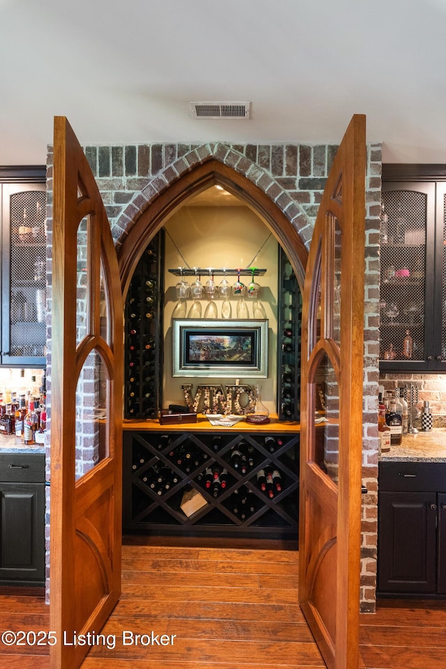 wine room featuring a dry bar, wood finished floors, and visible vents