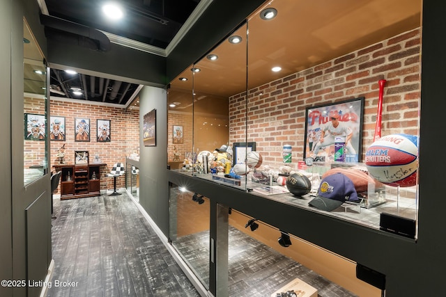 game room with brick wall and wood finished floors