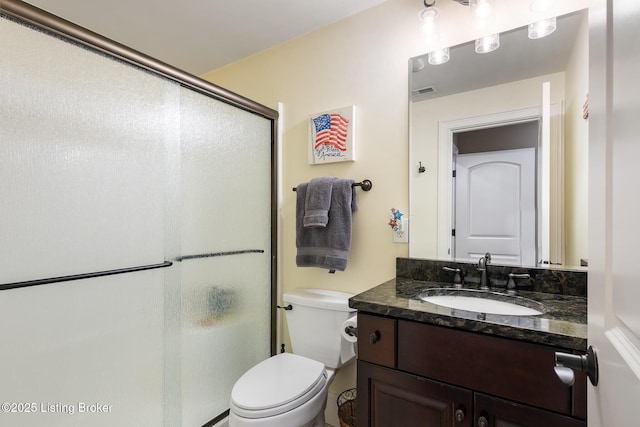 full bath with toilet, vanity, and a shower with shower door