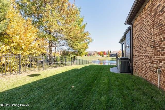 view of yard with a water view, a fenced backyard, and central air condition unit