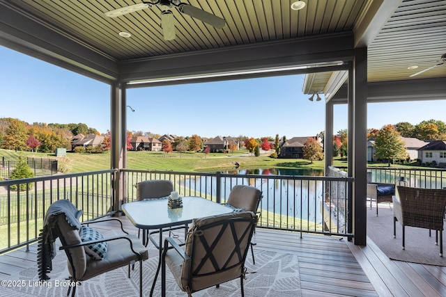 wooden deck with ceiling fan, a water view, and a residential view