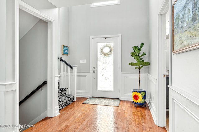 entrance foyer with wainscoting, stairway, and light wood-type flooring