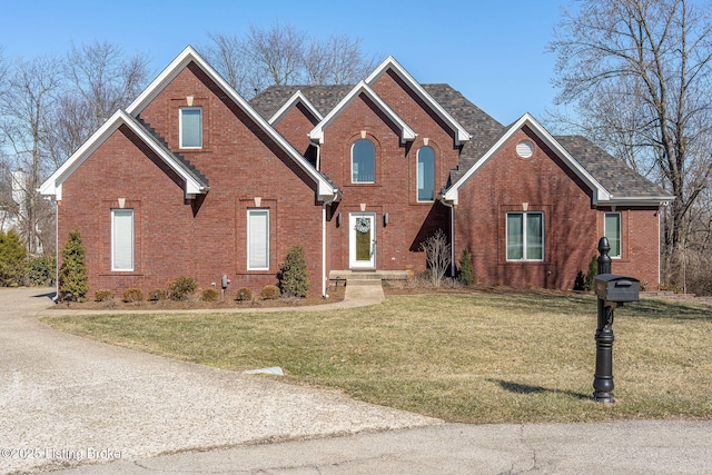 traditional home featuring a front yard and brick siding