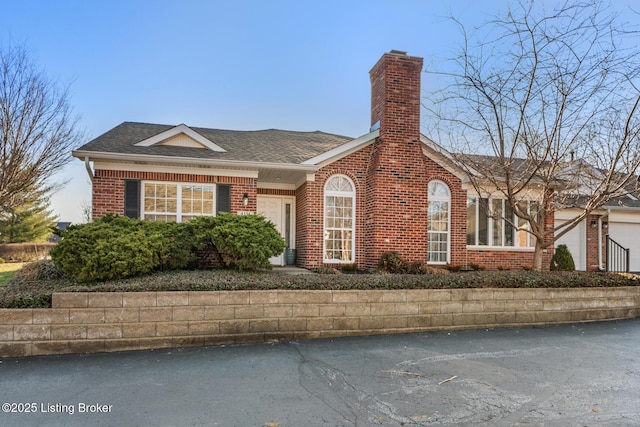 view of front of property with a shingled roof, brick siding, and a chimney