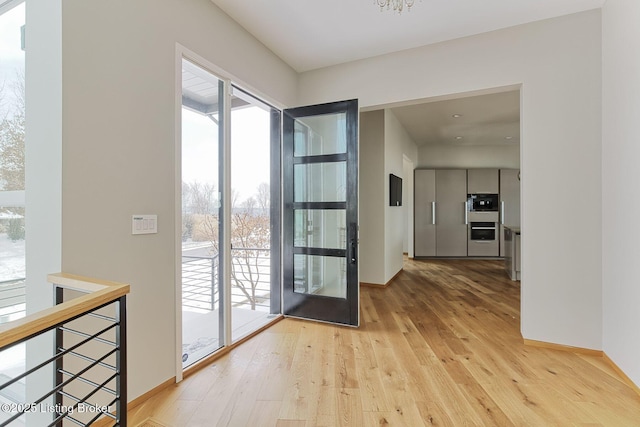 doorway with light wood-style floors and baseboards