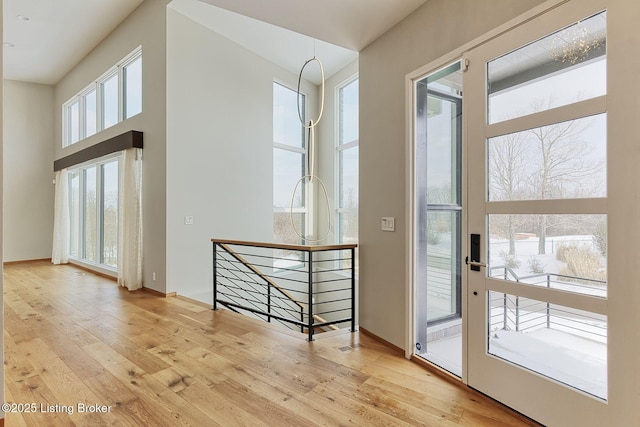 doorway featuring a high ceiling, baseboards, and hardwood / wood-style floors