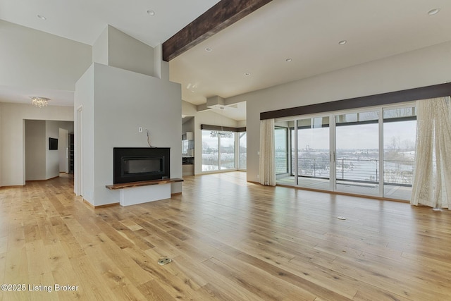 unfurnished living room with light wood-style floors, a glass covered fireplace, beam ceiling, and recessed lighting