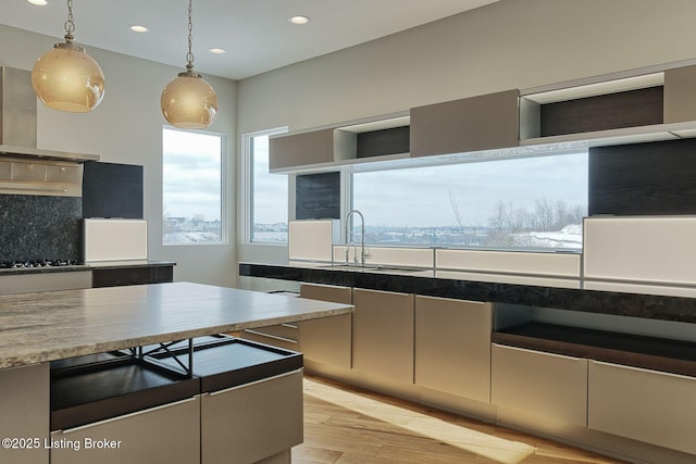 kitchen with gas cooktop, light wood-style flooring, recessed lighting, wall chimney range hood, and decorative light fixtures