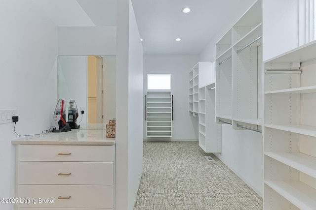 walk in closet with light colored carpet