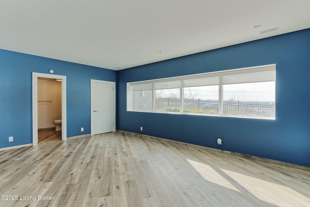 unfurnished bedroom with multiple windows, wood finished floors, and visible vents