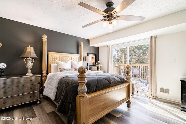 bedroom with a textured ceiling, access to outside, wood finished floors, and visible vents