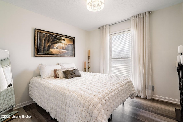 bedroom featuring a textured ceiling, dark wood-style flooring, and baseboards