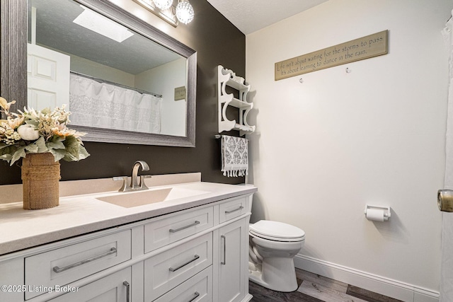 full bath featuring a textured ceiling, toilet, wood finished floors, vanity, and baseboards