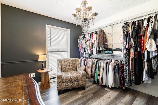 spacious closet with a notable chandelier and wood finished floors