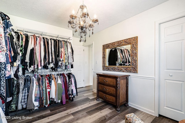 walk in closet with a chandelier and wood finished floors