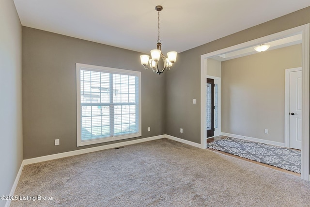 empty room with carpet floors, a chandelier, visible vents, and baseboards