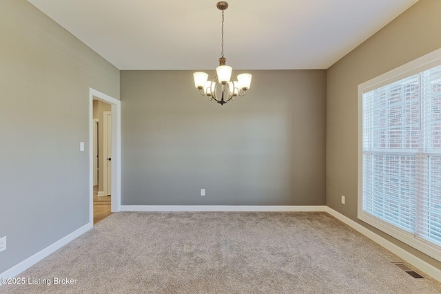 carpeted empty room with a chandelier, visible vents, and baseboards