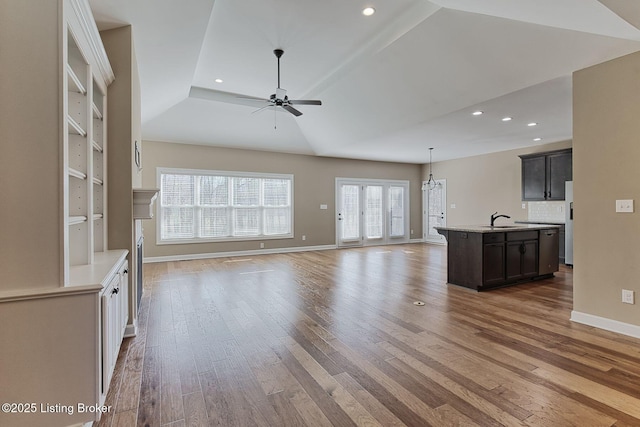 unfurnished living room featuring recessed lighting, a ceiling fan, a sink, wood finished floors, and baseboards