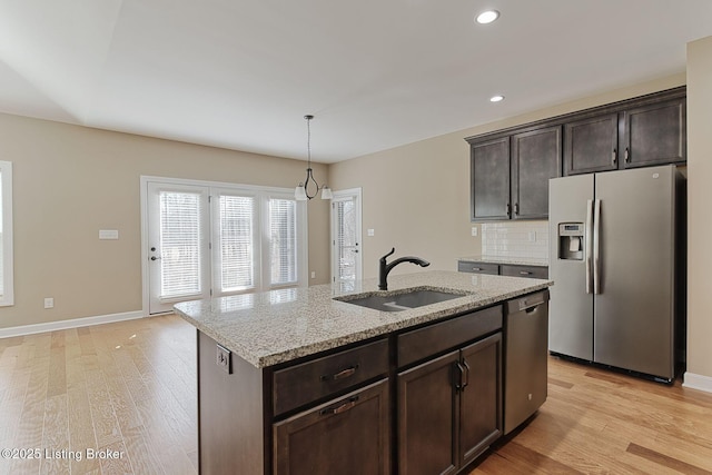 kitchen with light wood-style flooring, appliances with stainless steel finishes, dark brown cabinets, and a sink