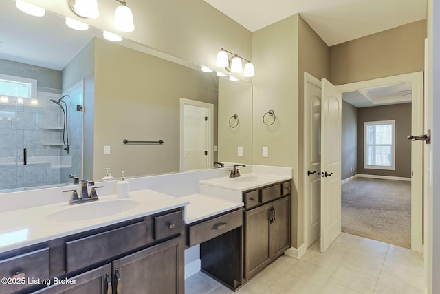 full bathroom featuring double vanity, tiled shower, a sink, and baseboards