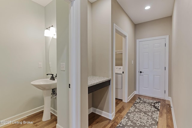 interior space with washer / dryer, a sink, baseboards, and wood finished floors