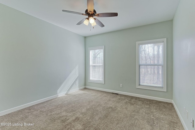 unfurnished room with carpet floors, visible vents, baseboards, and a ceiling fan