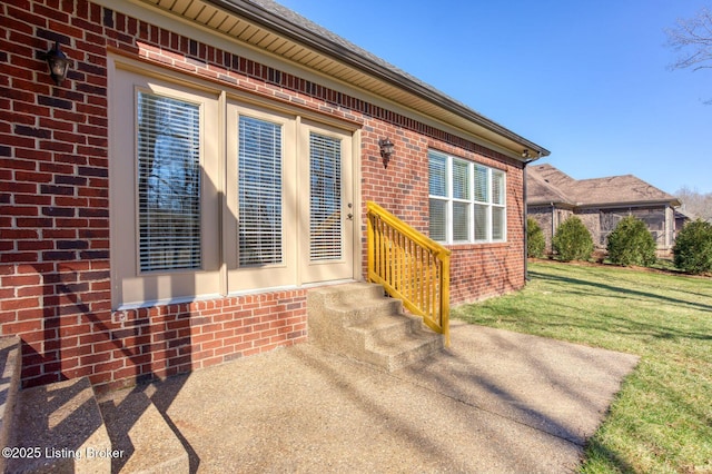 entrance to property featuring a yard and brick siding