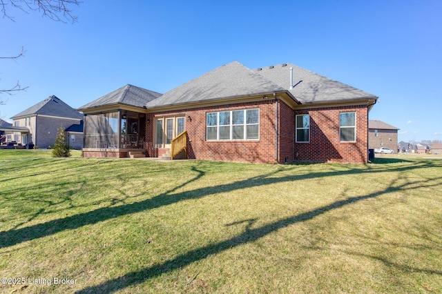 back of property with brick siding, a lawn, a shingled roof, and a sunroom