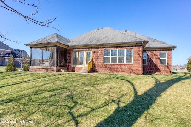 rear view of house featuring a sunroom, roof with shingles, a lawn, and brick siding