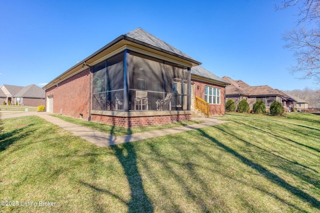 exterior space featuring a garage, a sunroom, a yard, and brick siding