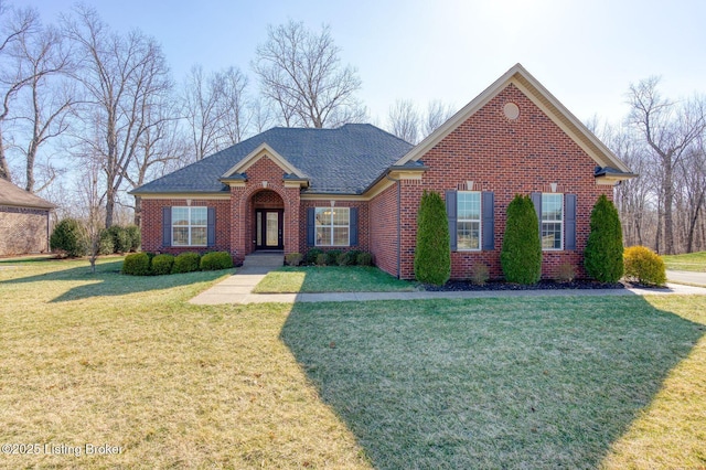 view of front of property with a shingled roof, brick siding, and a front lawn