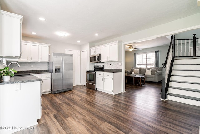 kitchen with stainless steel appliances, dark wood-type flooring, dark countertops, and a sink