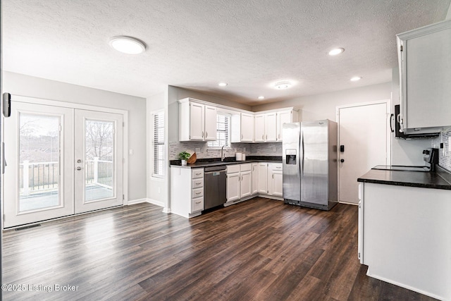 kitchen with dark countertops, dark wood-style floors, appliances with stainless steel finishes, and backsplash