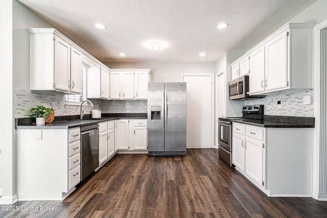 kitchen with appliances with stainless steel finishes, dark wood finished floors, white cabinetry, and a sink