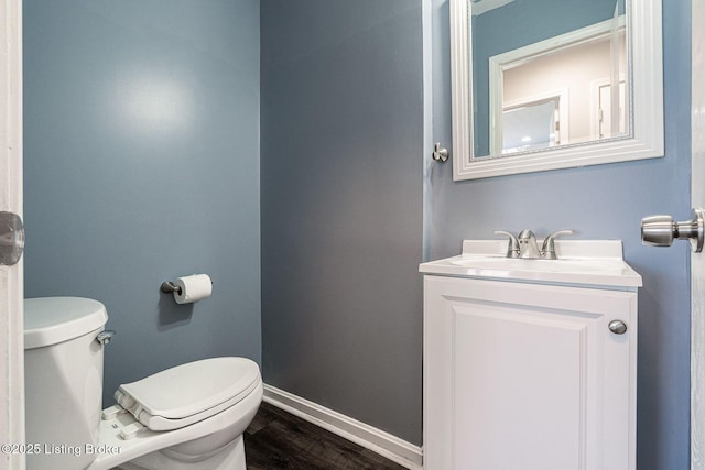 bathroom featuring toilet, baseboards, wood finished floors, and vanity