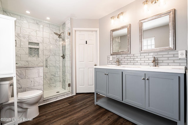 bathroom with a stall shower, tasteful backsplash, toilet, wood finished floors, and a sink