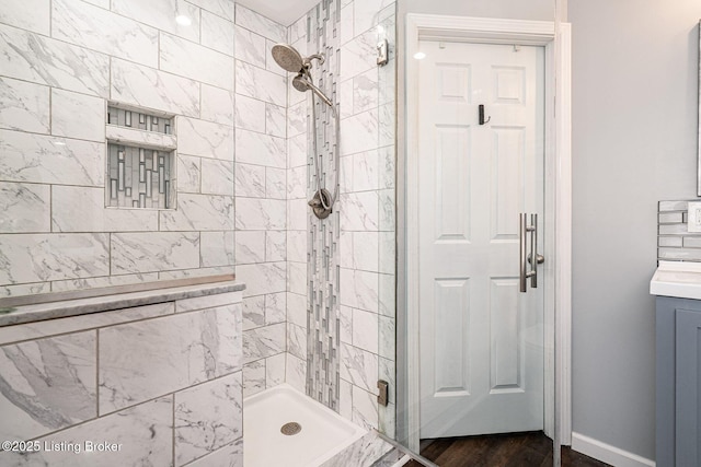 bathroom featuring a stall shower, vanity, baseboards, and wood finished floors