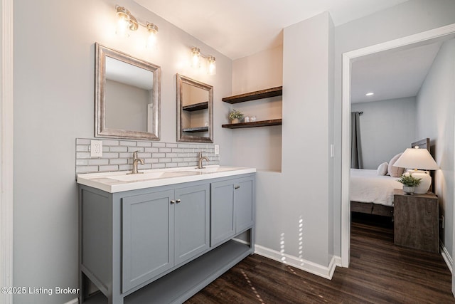 full bathroom featuring double vanity, tasteful backsplash, baseboards, wood finished floors, and a sink