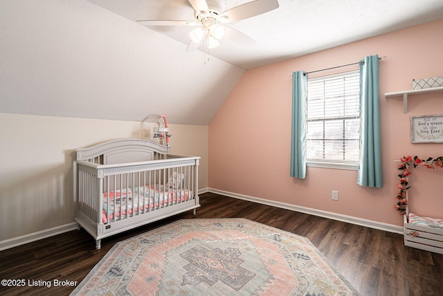 bedroom featuring a crib, baseboards, a ceiling fan, lofted ceiling, and wood finished floors