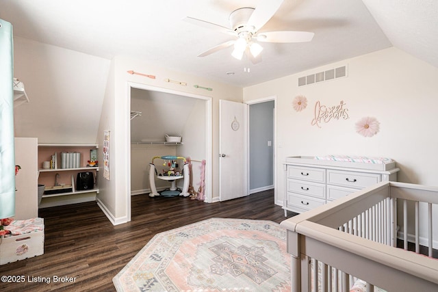 bedroom featuring lofted ceiling, visible vents, a closet, dark wood-style floors, and a crib