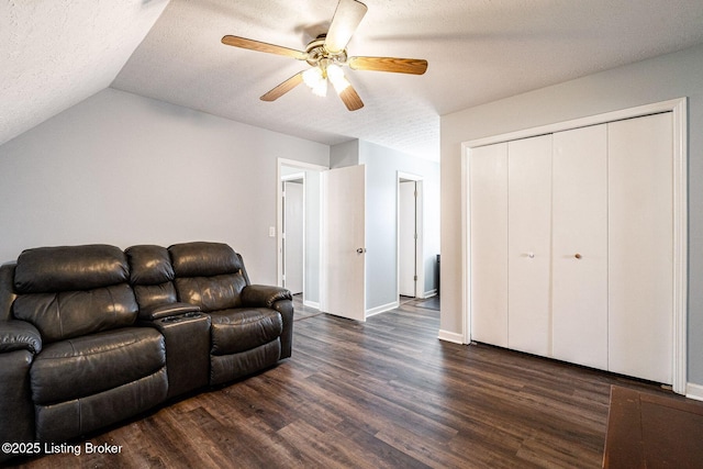 living room with dark wood-type flooring, a ceiling fan, vaulted ceiling, a textured ceiling, and baseboards