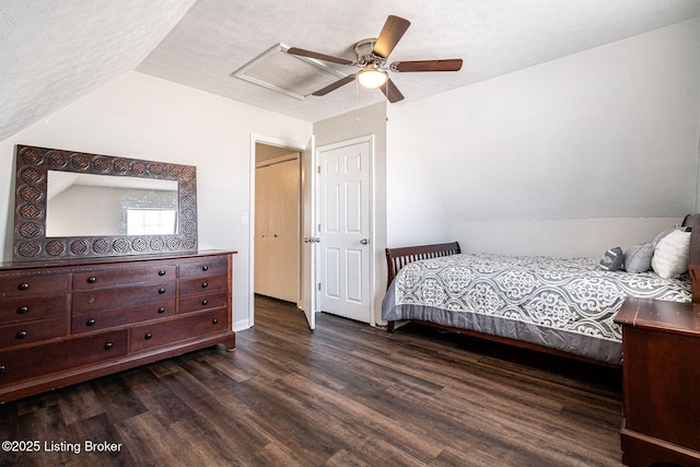 bedroom featuring dark wood-type flooring, lofted ceiling, attic access, and a textured ceiling