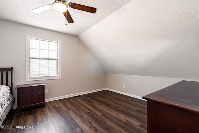 bedroom featuring lofted ceiling, a textured ceiling, baseboards, and wood finished floors